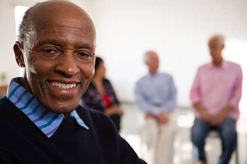 Close up Portrait of smiling senior man with friends in background at art class