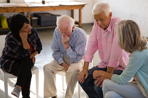 Female of friends consoling worried male friends while sitting in art class