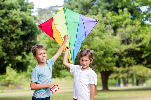 Two happy boys holding a kite in park