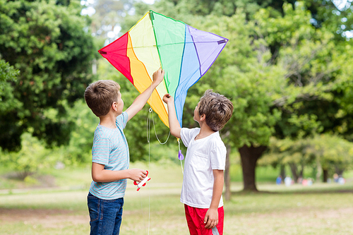 Two happy boys holding a kite in park
