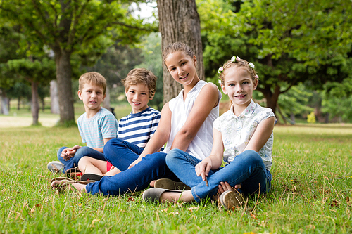 Portrait of kids sitting together in park on a sunny day