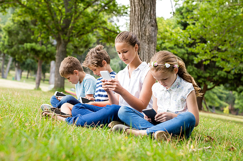 Kids using mobile phone in park on a sunny day