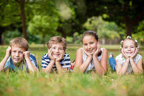 Portrait of happy children lying on grass in park