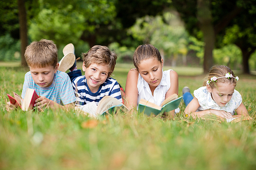 Kids lying on grass and reading books in park