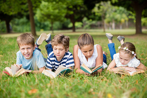 Kids lying on grass and reading books in park