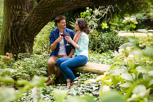Romantic couple toasting a glass of red wine in garden on a sunny day
