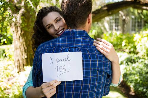 Couple holding I sad yes paper while embracing each other in garden