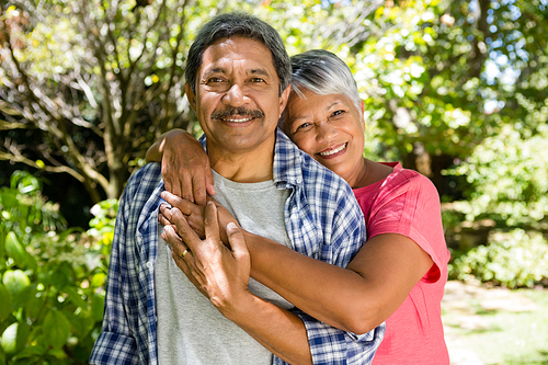 Portrait of senior couple embracing each other in garden on a sunny day