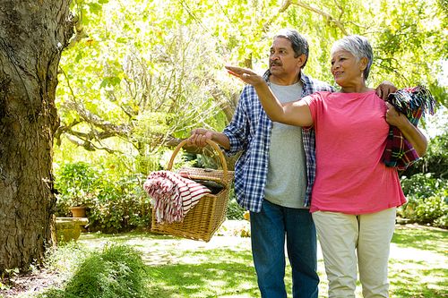 Senior couple walking in garden with basket at the park
