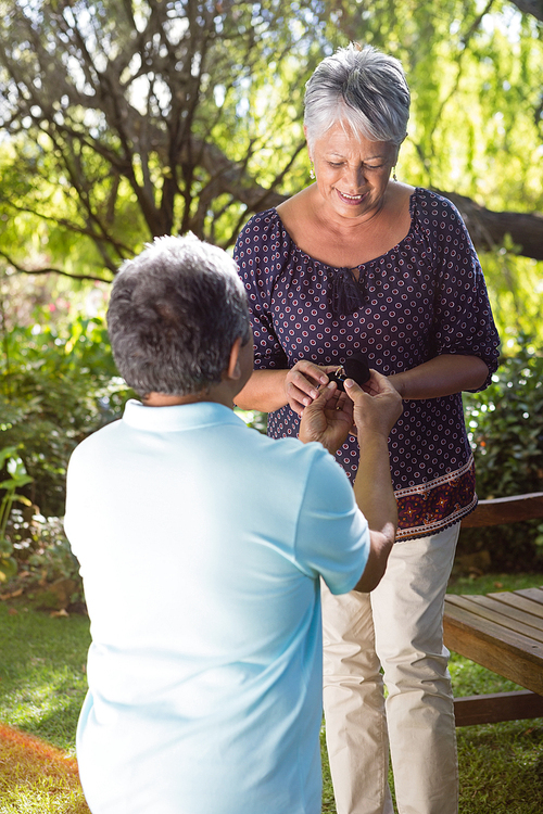 Senior man proposing woman by gifting ring in garden