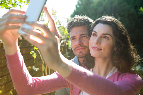 Smiling couple taking selfie on mobile phone in garden