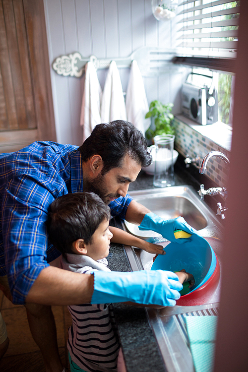 High angle view of father assisting son for cleaning utensils at home
