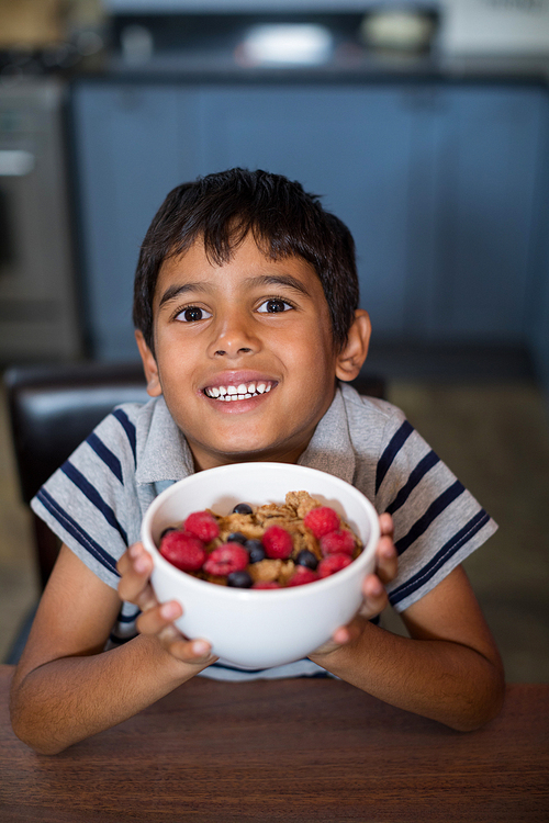 Close up portrait of boy showing cereal breakfast while sitting by table at home