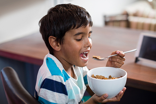 Close up of boy having cereal breakfast at home