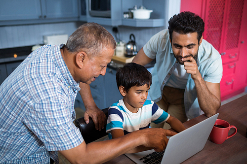 High angle view of father and grandfather looking at boy using laptop