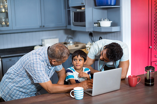 Father and grandfather talking to boy while sitting at home