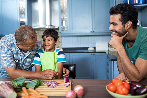 Man looking at happy boy and grandfather while preparing food