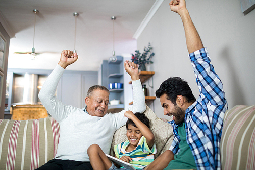 Cheerful family with arms raised siting on sofa in living room at home