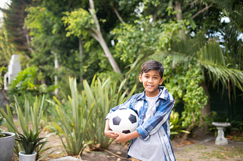 Portrait of boy holding soccer ball while standing at park