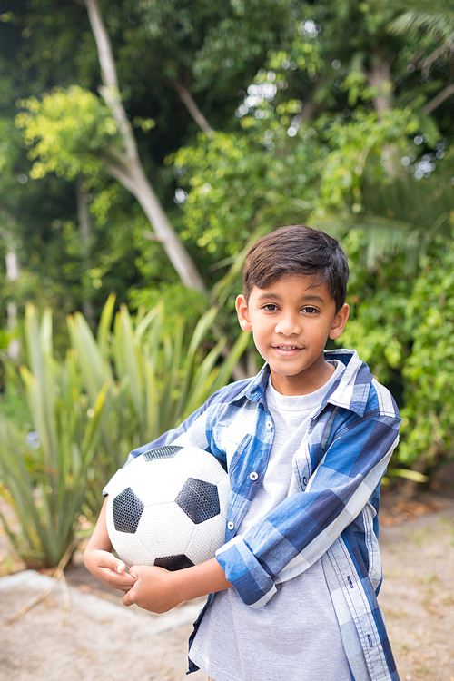 Portrait of smiling boy holding soccer ball while standing at park