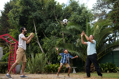 Family playing with soccer ball against plants at park
