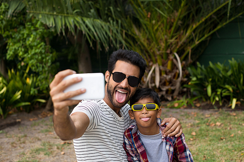 Playful father and son wearing sunglases while taking selfie