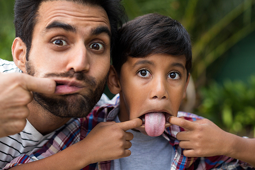 Portrait of father and son teasing while playing in yard
