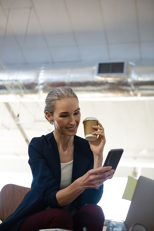 Businesswoman using mobile phone while sitting at table in office