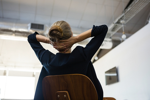 Low angle view of businesswoman with hands behind head relaxing in office