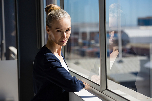 Portrait of confident woman standing by window in office