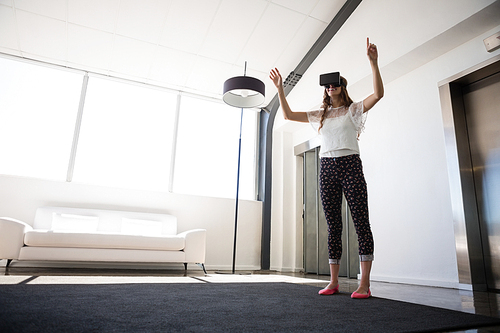 Full length of businesswoman wearing virtual reality simulator in office