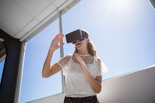 Low angle view of happy businesswoman using virtual reality simulator by window