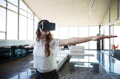 Smiling businesswoman using virtual reality simulator exercising while standing in office