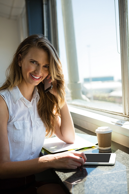 Portrait of smiling businesswoman talking on mobile phone by window at office