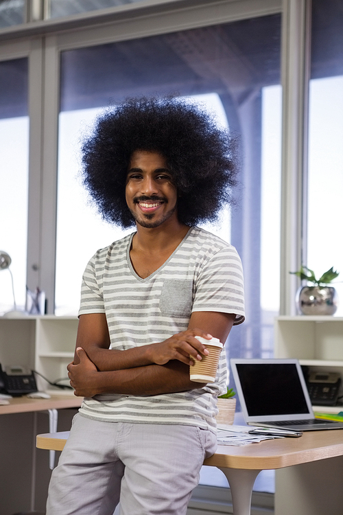 Portrait of smiling young man holding coffee cup at office