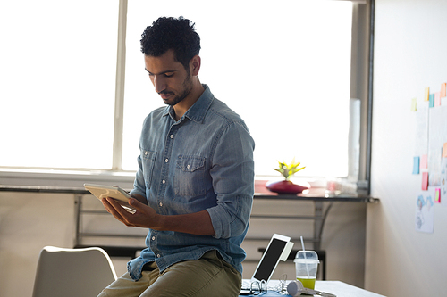 Man using tablet while sitting on desk in office