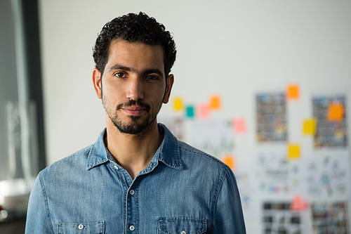 Portrait of confident young man standing in creative office