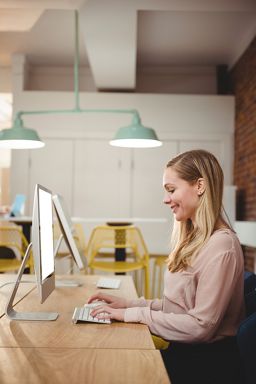 Smiling female executive working on computer in office