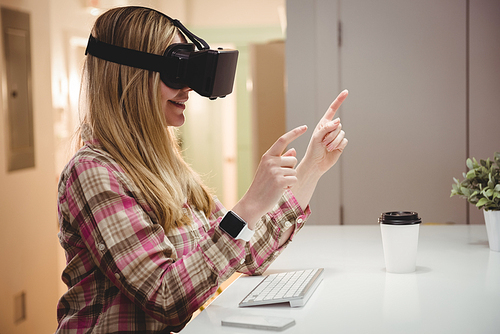 Smiling female executive using virtual reality headset in office