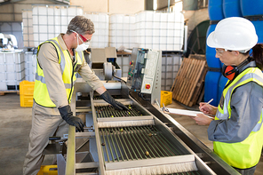 Technicians examining olives on conveyor belt in oil factory