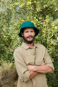 Portrait of smiling farmer standing with arms crossed in olive farm