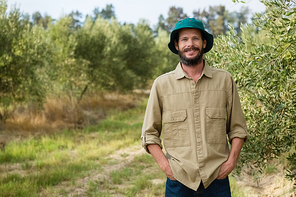 Portrait of smiling farmer standing with hands in pocket in olive farm