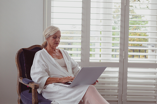 Front view of active senior Caucasian woman sitting on chair in a comfortable home
