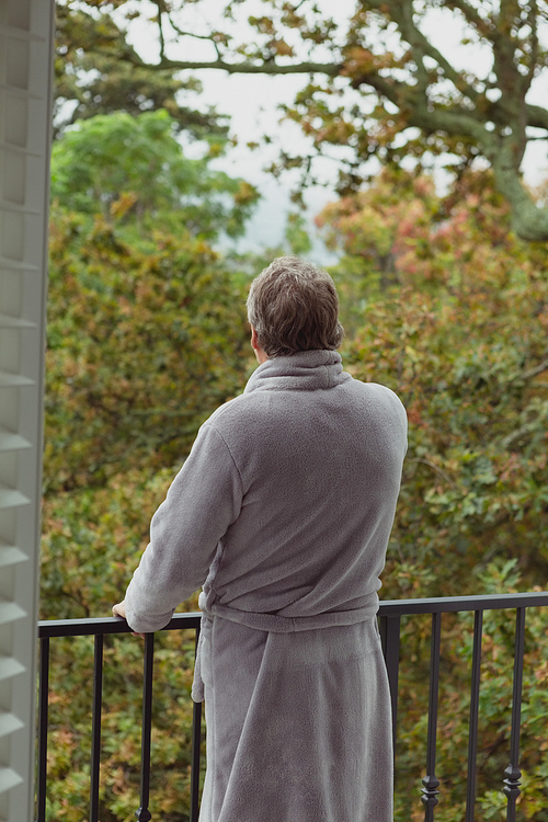 Rear view of active senior Caucasian man standing in balcony in a comfortable home