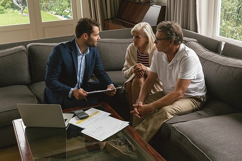 High view of active senior Caucasian couple discussing with real estate agent in living room at home