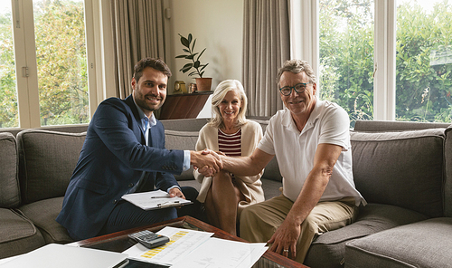 Front view of active senior Caucasian man shaking hands with real estate agent in living room at home