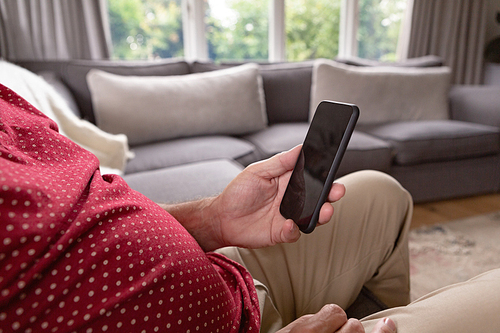 Mid section of active senior Caucasian man using mobile phone on sofa in a comfortable home