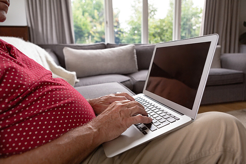 Mid section of active senior Caucasian man using laptop on sofa in a comfortable home
