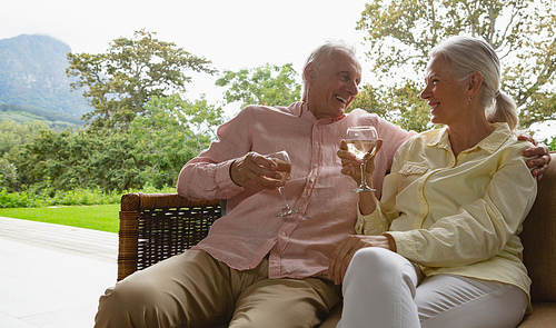 Front view of active senior Caucasian couple having champagne in the porch at home
