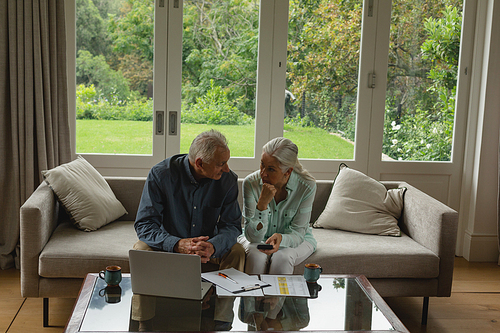 High view of active senior Caucasian couple calculating bills in living room at home